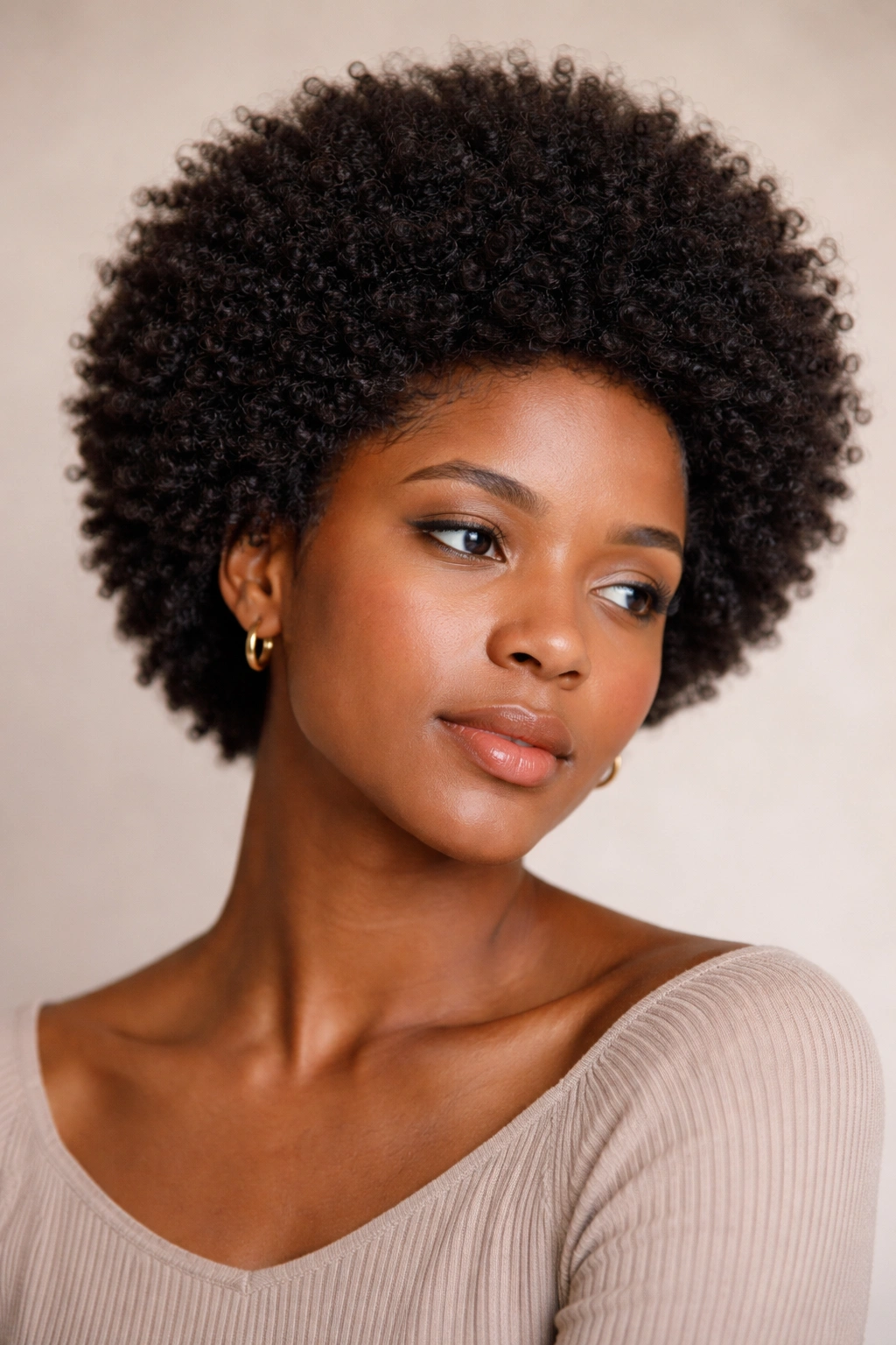 Close-up portrait of a person with dense, well-defined afro showing 4C texture, calm expression, minimalist backdrop