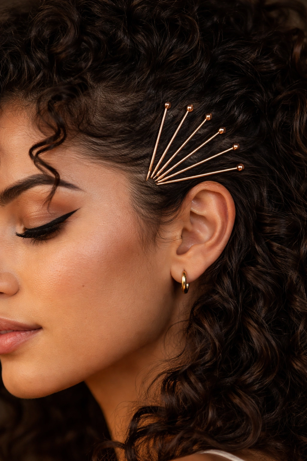 Temple-area close-up with bobby pins arranged in a fan pattern.