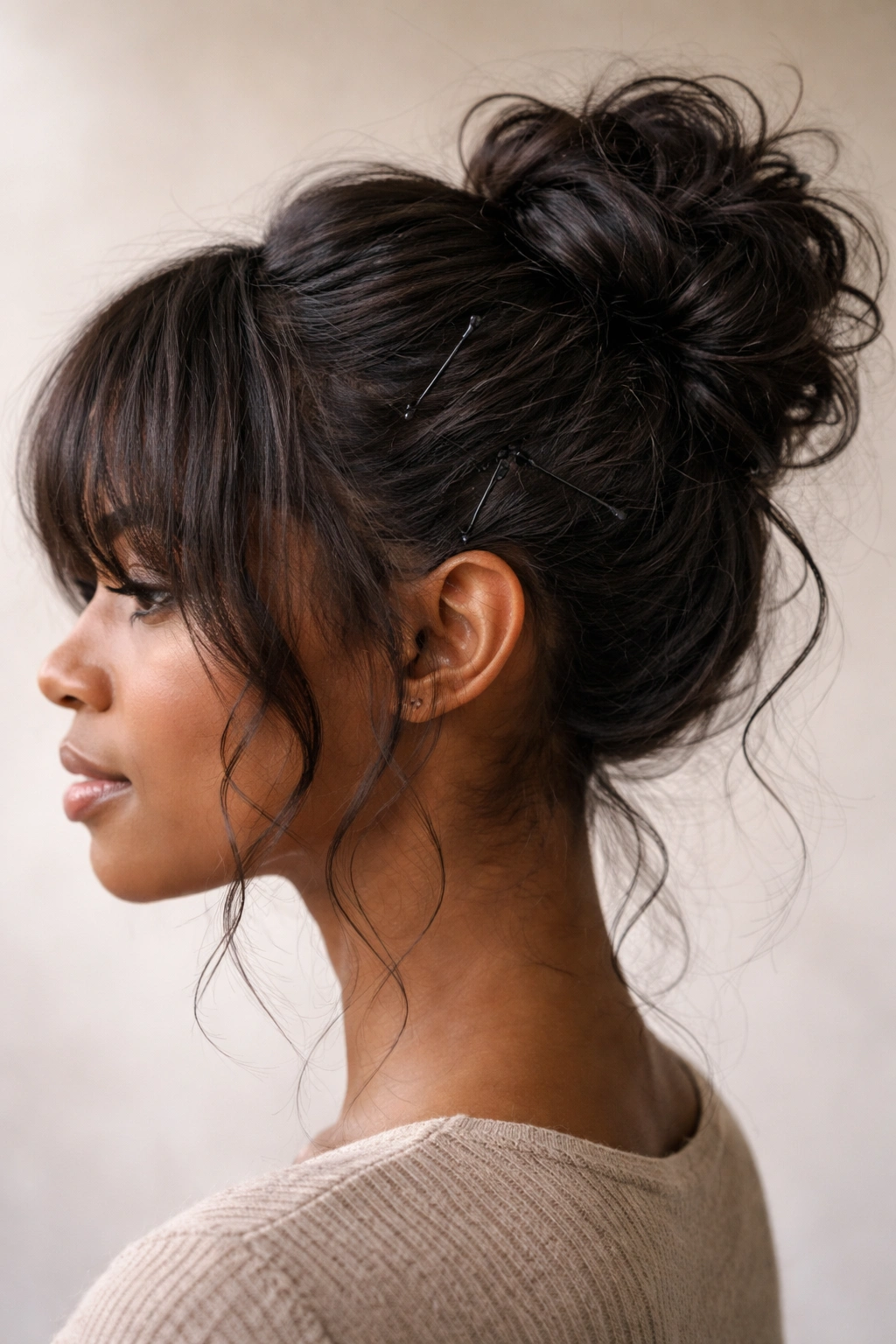 Side view of a textured bun secured with bobby pins and some loose strands.