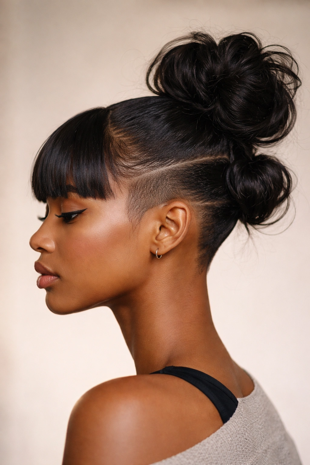 Portrait of a double-section bun with undercut fade and blunt bangs on Black hair.