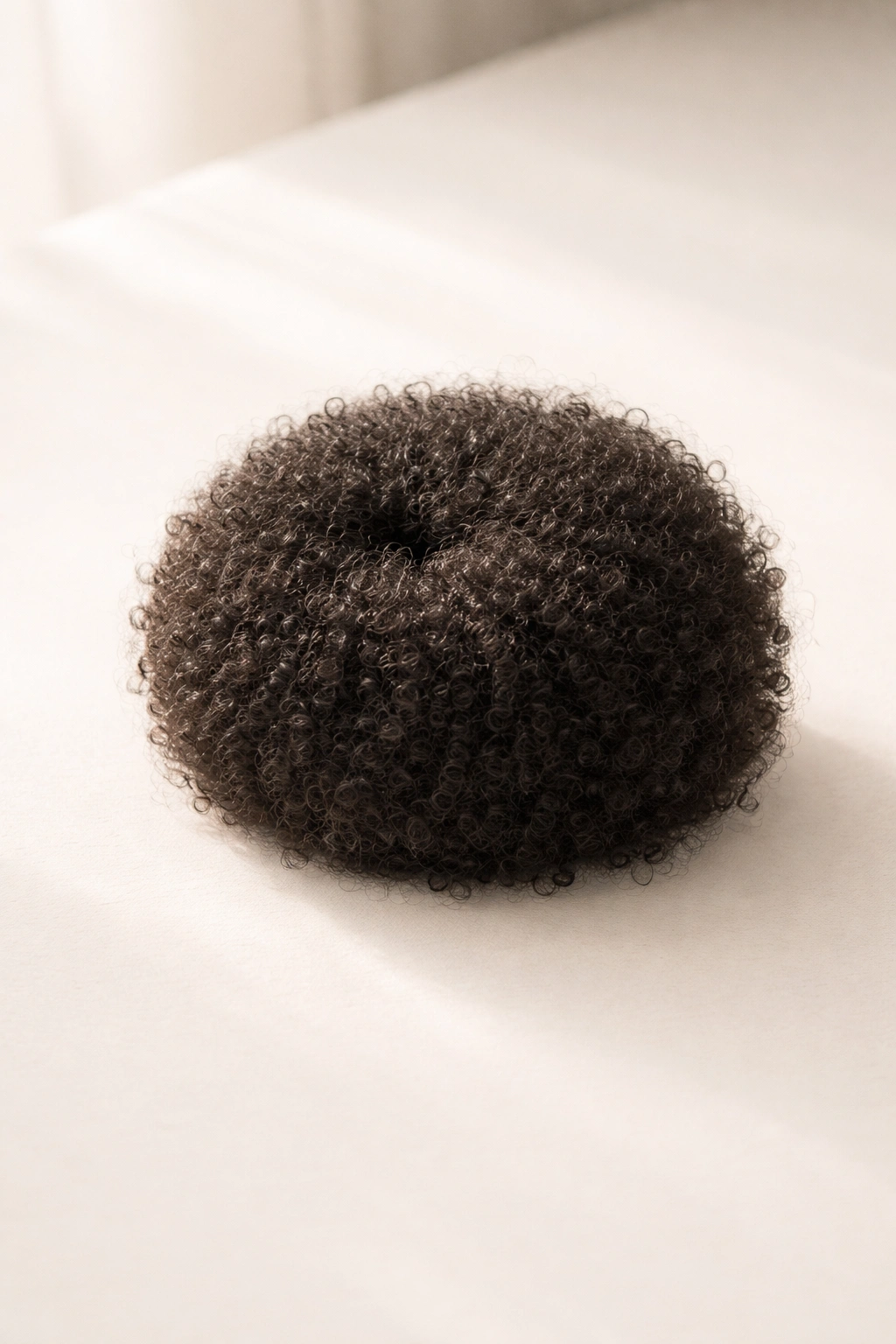 Minimalist image of a single afro bun on a clean surface