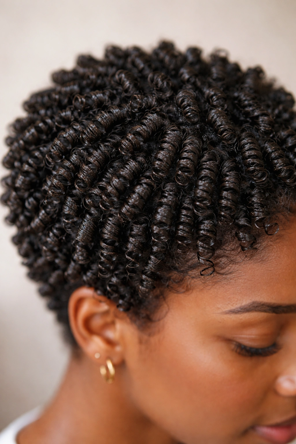 Close-up of finger coils on short 4C hair showing defined spirals and moisture sheen