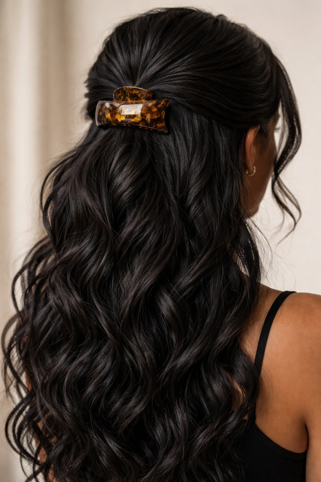 Half-up hairstyle with large tortoiseshell clip securing the gathered section