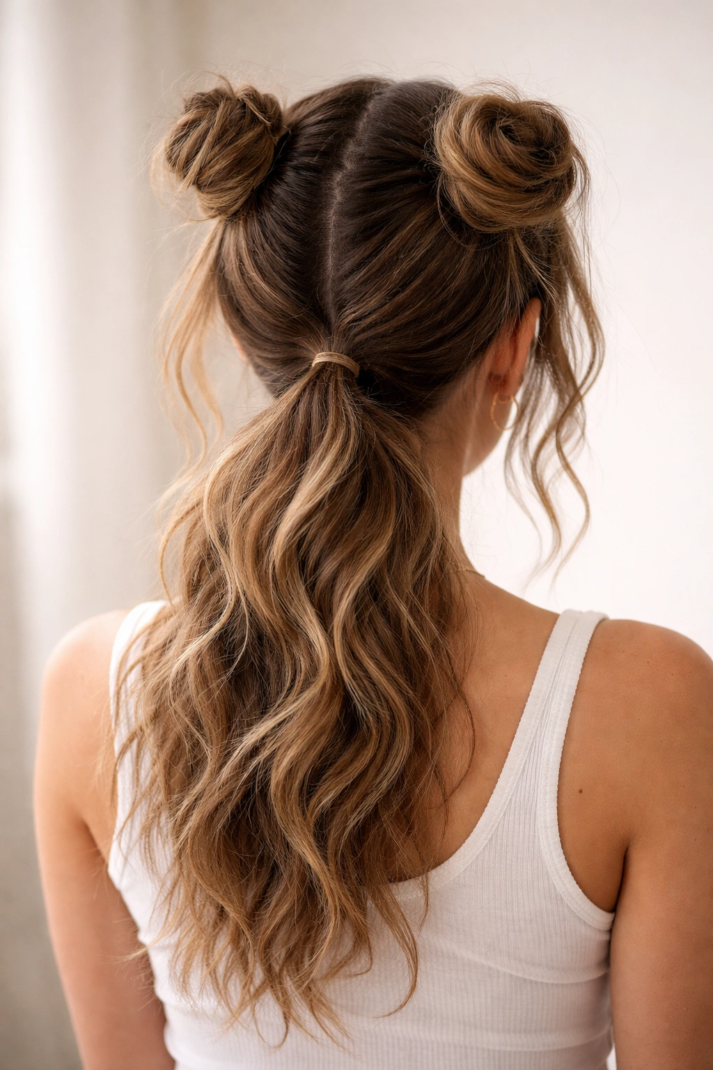 Two space buns above a loose wavy ponytail