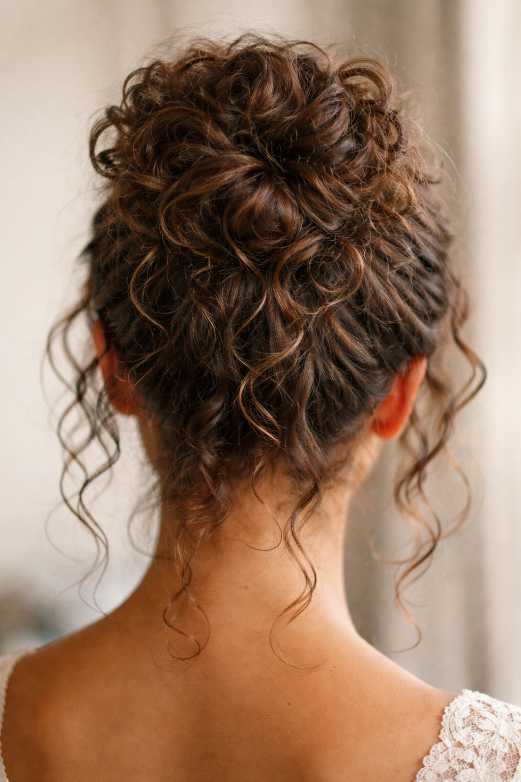 Back view of curly hair in a textured loose bun with defined curls