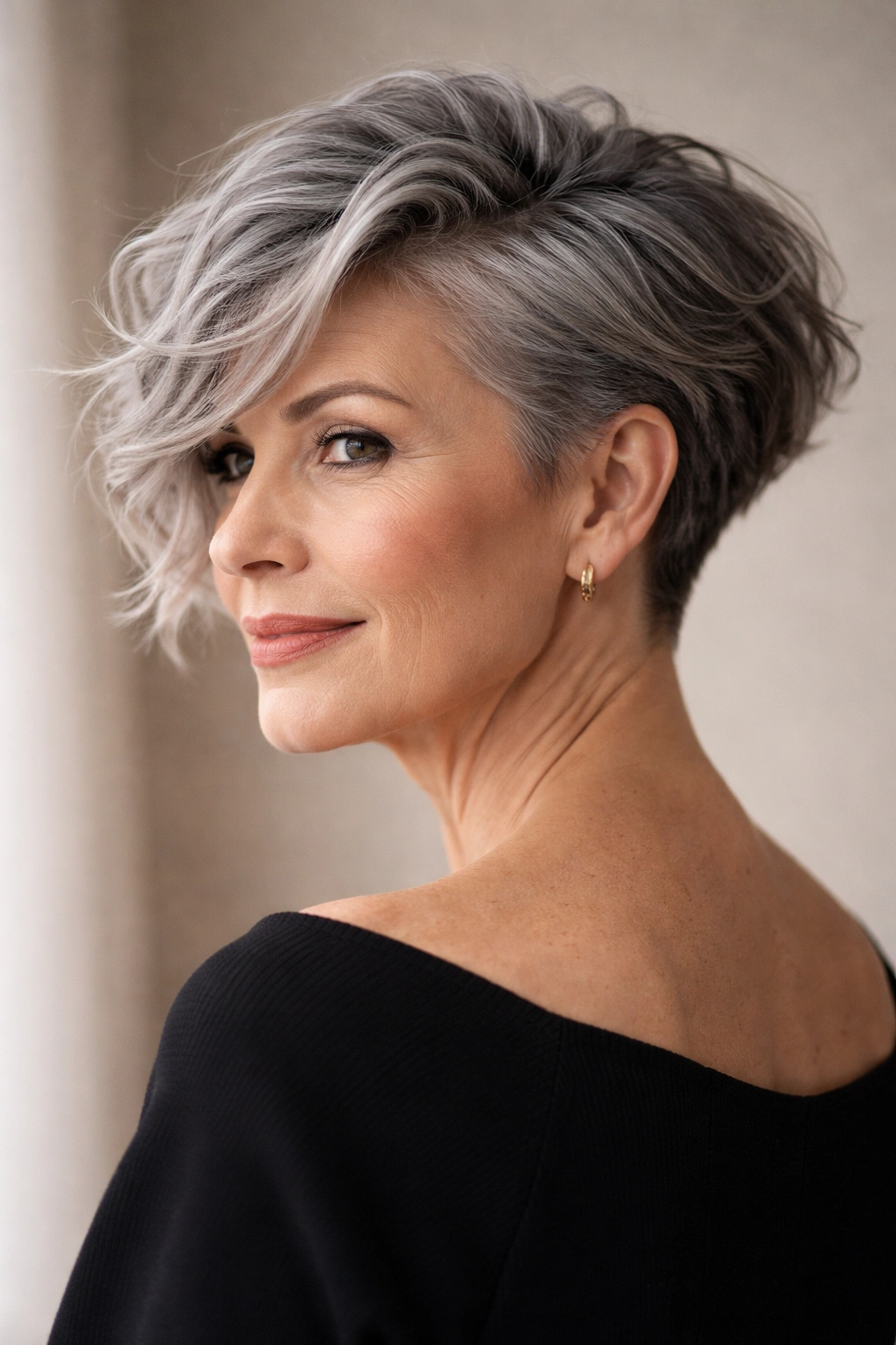 Portrait of a silver-haired model with a long, wavy top and a short undercut at the nape in a studio.