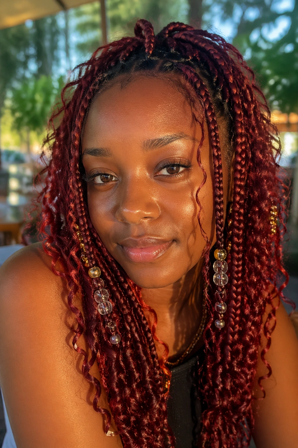 Close-up of a real person with boho red knotless box braids including curly pieces and beads