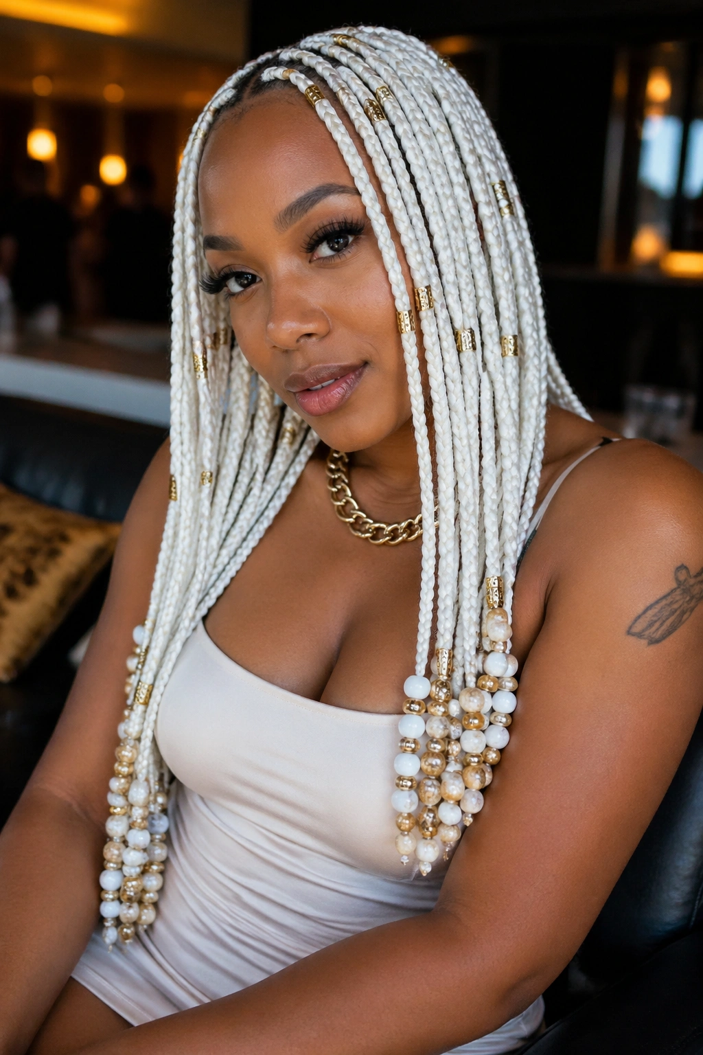 Real person wearing white box braids with gold cuffs in a lounge setting
