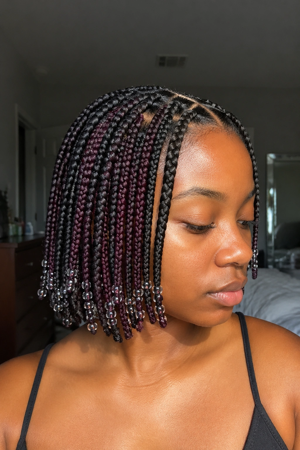 Close-up of short knotless box braids with deep plum peekaboo and tiny glass beads on a real woman