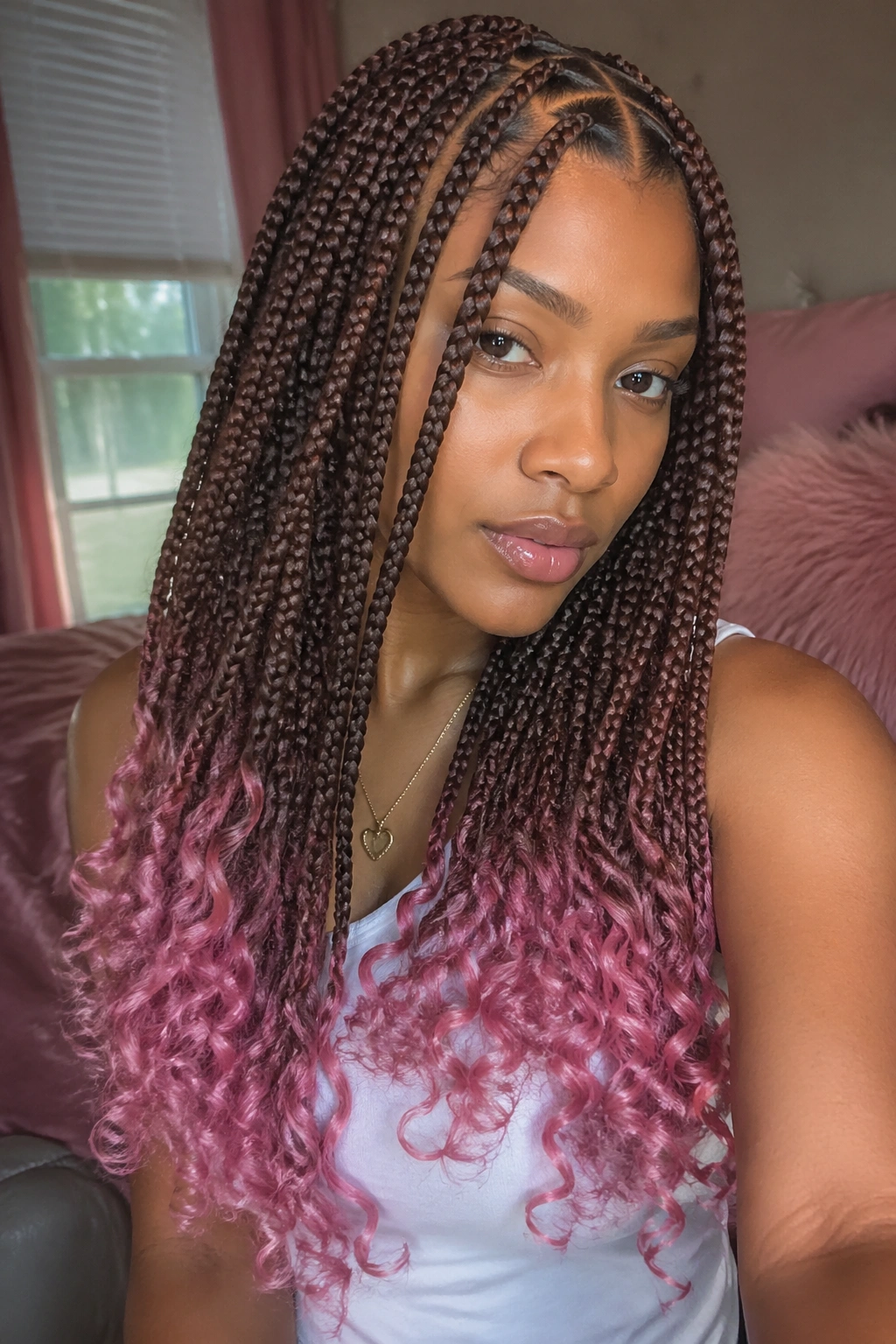 Close-up of a real person with triangle-part box braids and rose pink dip-dyed ends in warm window light