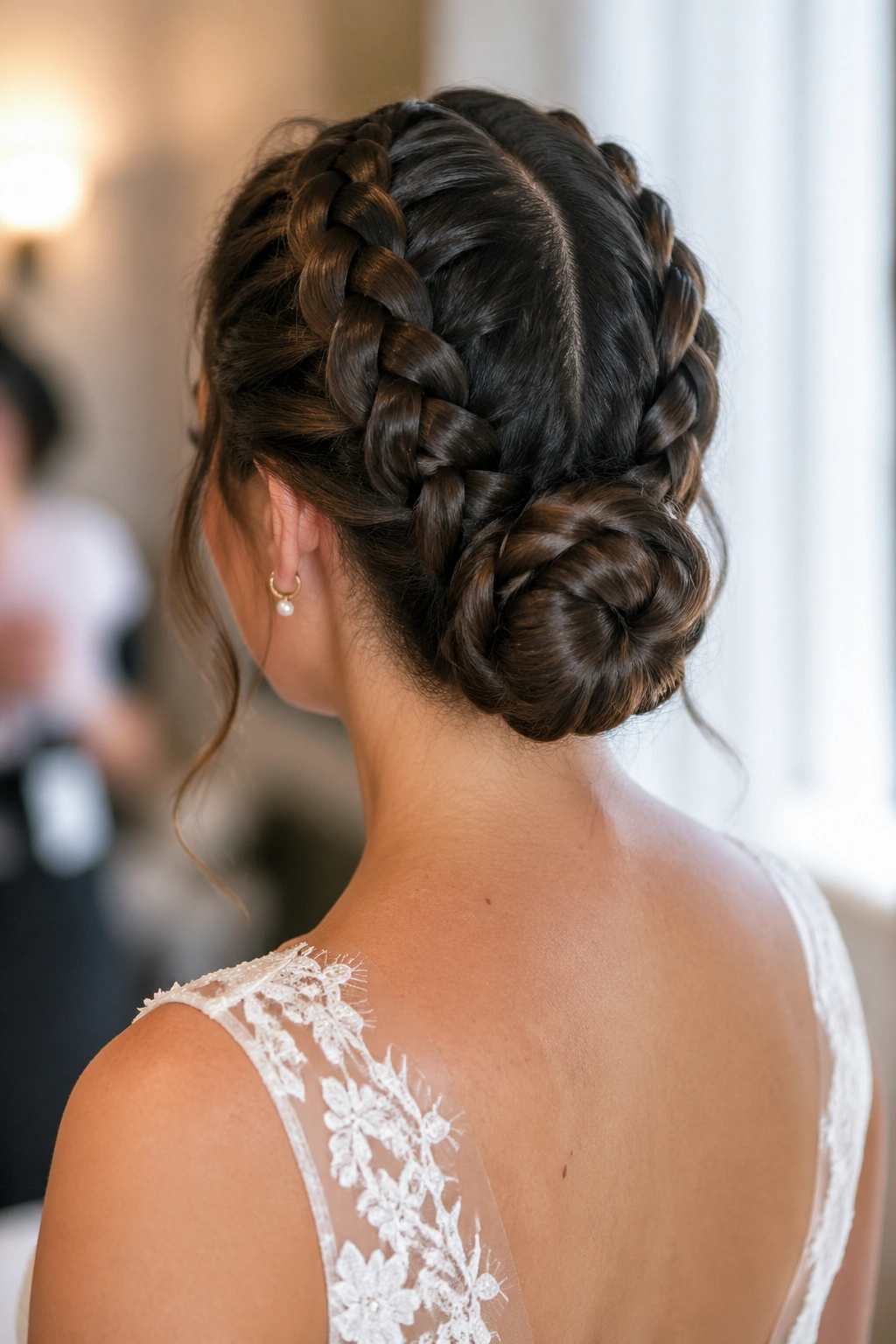 Rear view of a bride with two Dutch braids rolled into a single bun at the neck.