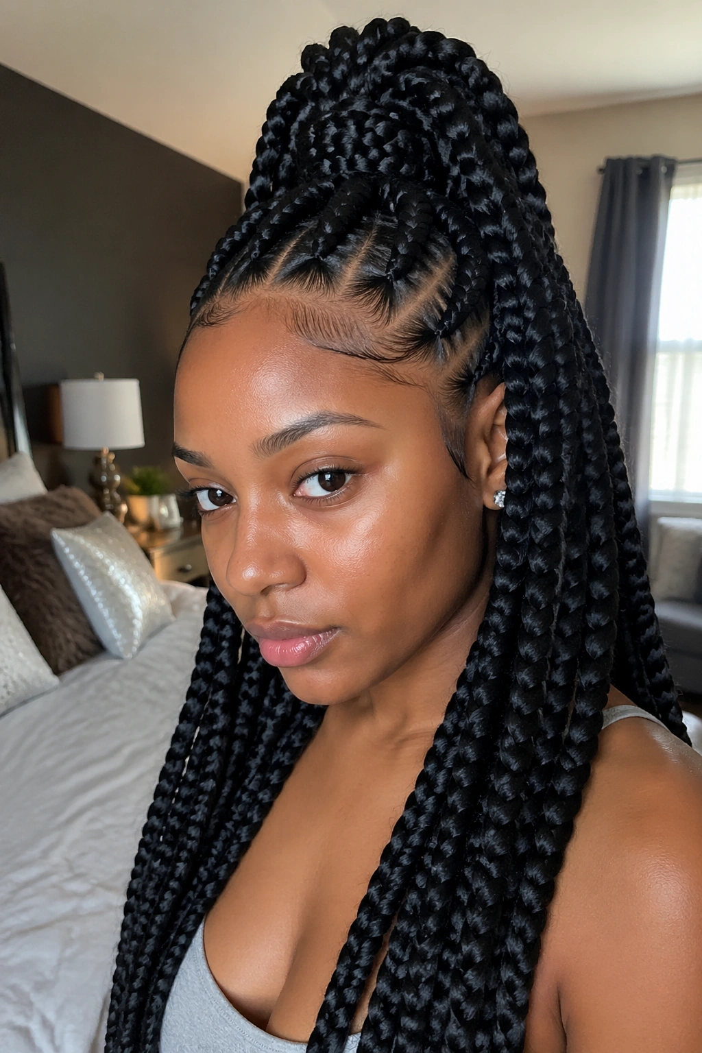 Close-up of a real woman with half-up jumbo feed-in braids in a cozy bedroom with natural light
