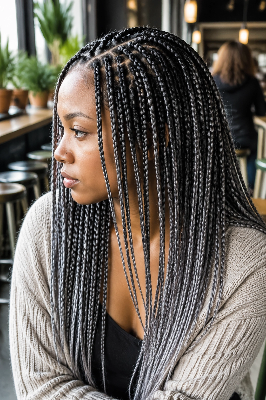 Knotless grey highlighted box braids close-up on a real person in a bright cafe