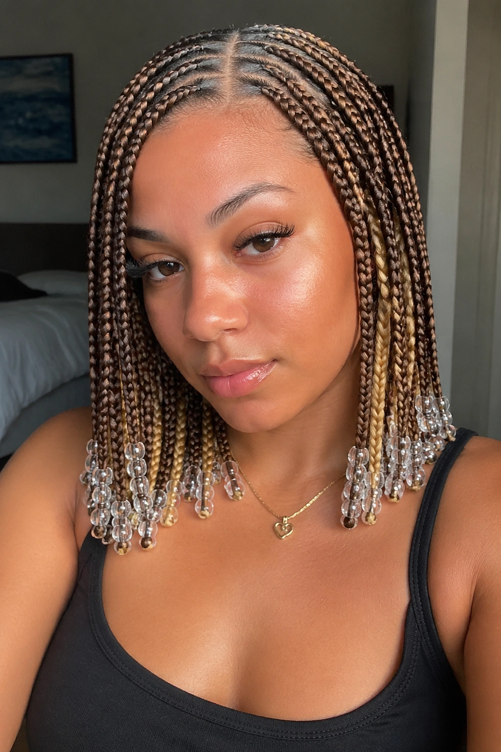 Close-up portrait of a real woman with honey-blonde knotless braids and clear beads peeking at the nape