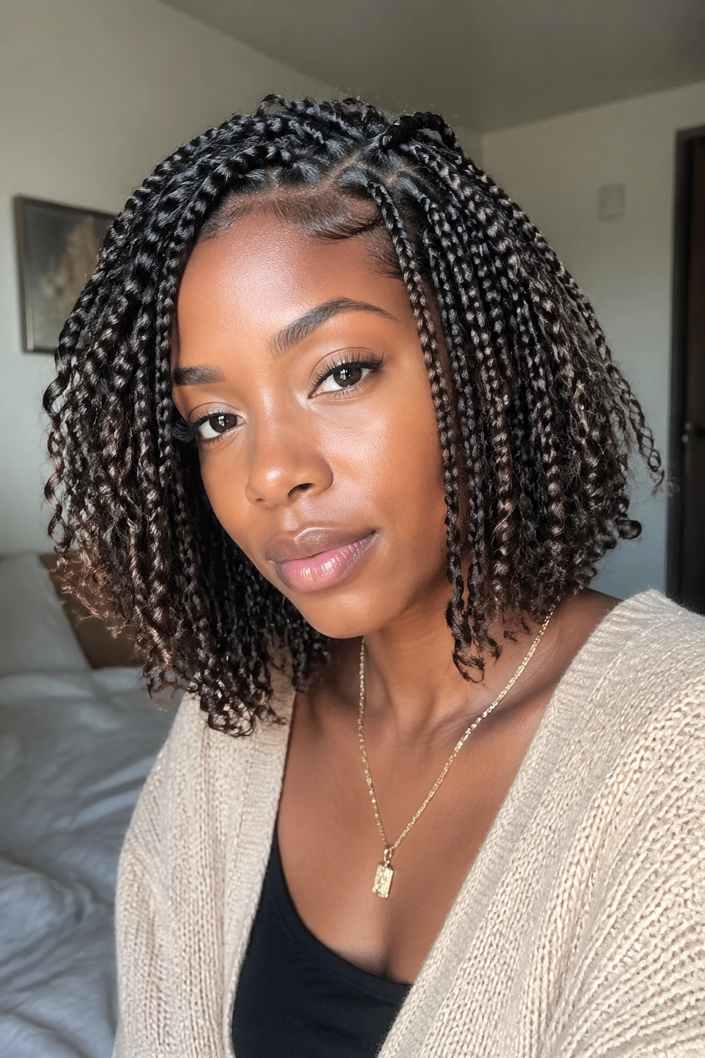 Close-up of a real woman with layered bob-length boho box braids in warm window light.