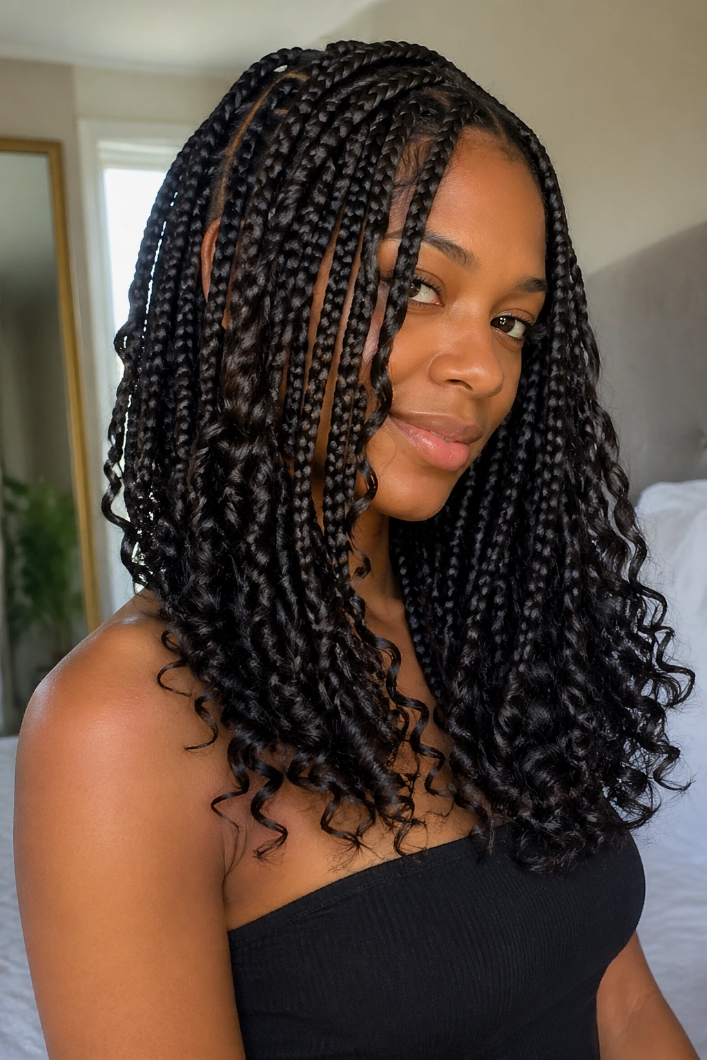 Close-up of layered medium box braids with curly ends on a real woman