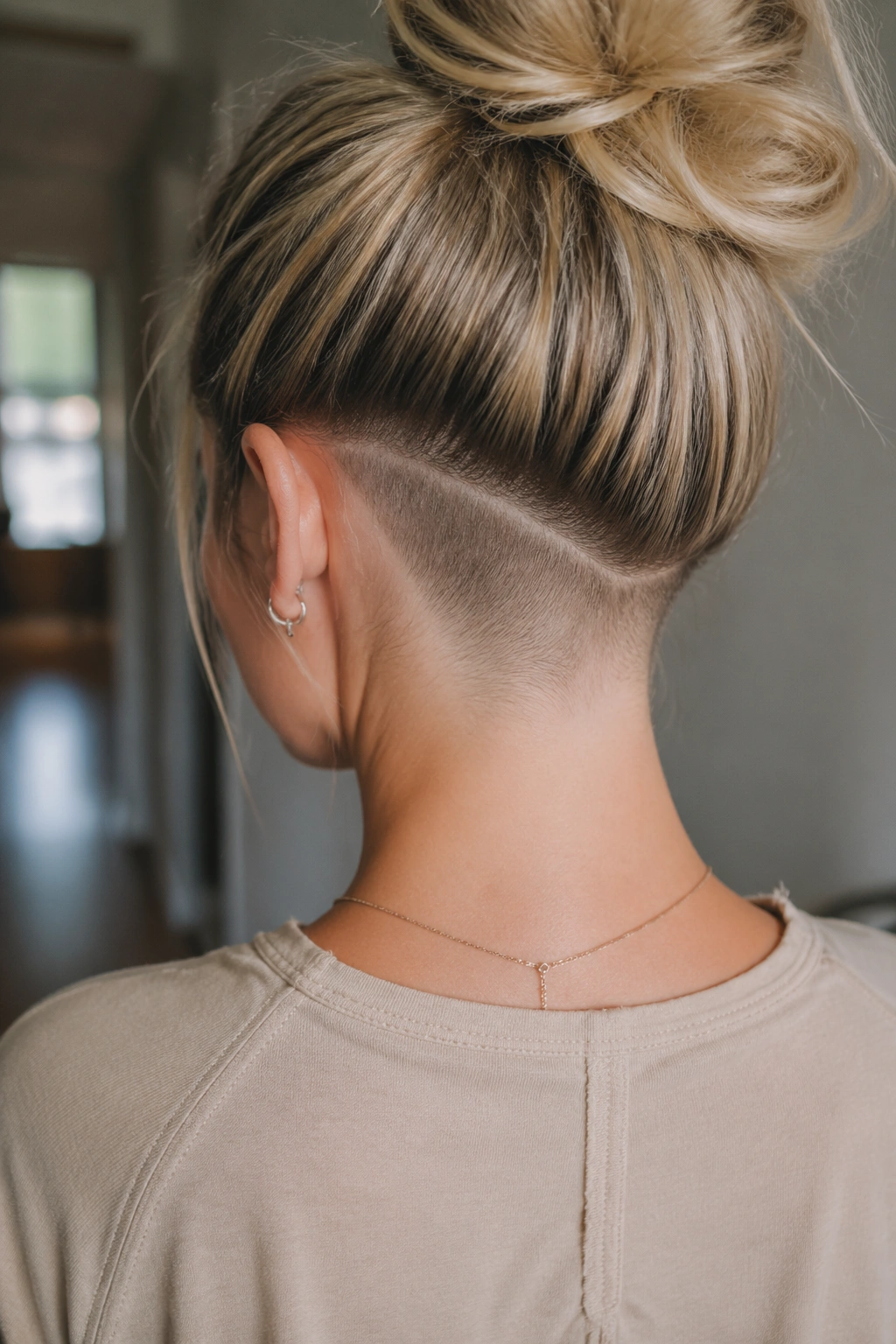 Back view of a real person showcasing a curved nape shave in a softly lit hallway