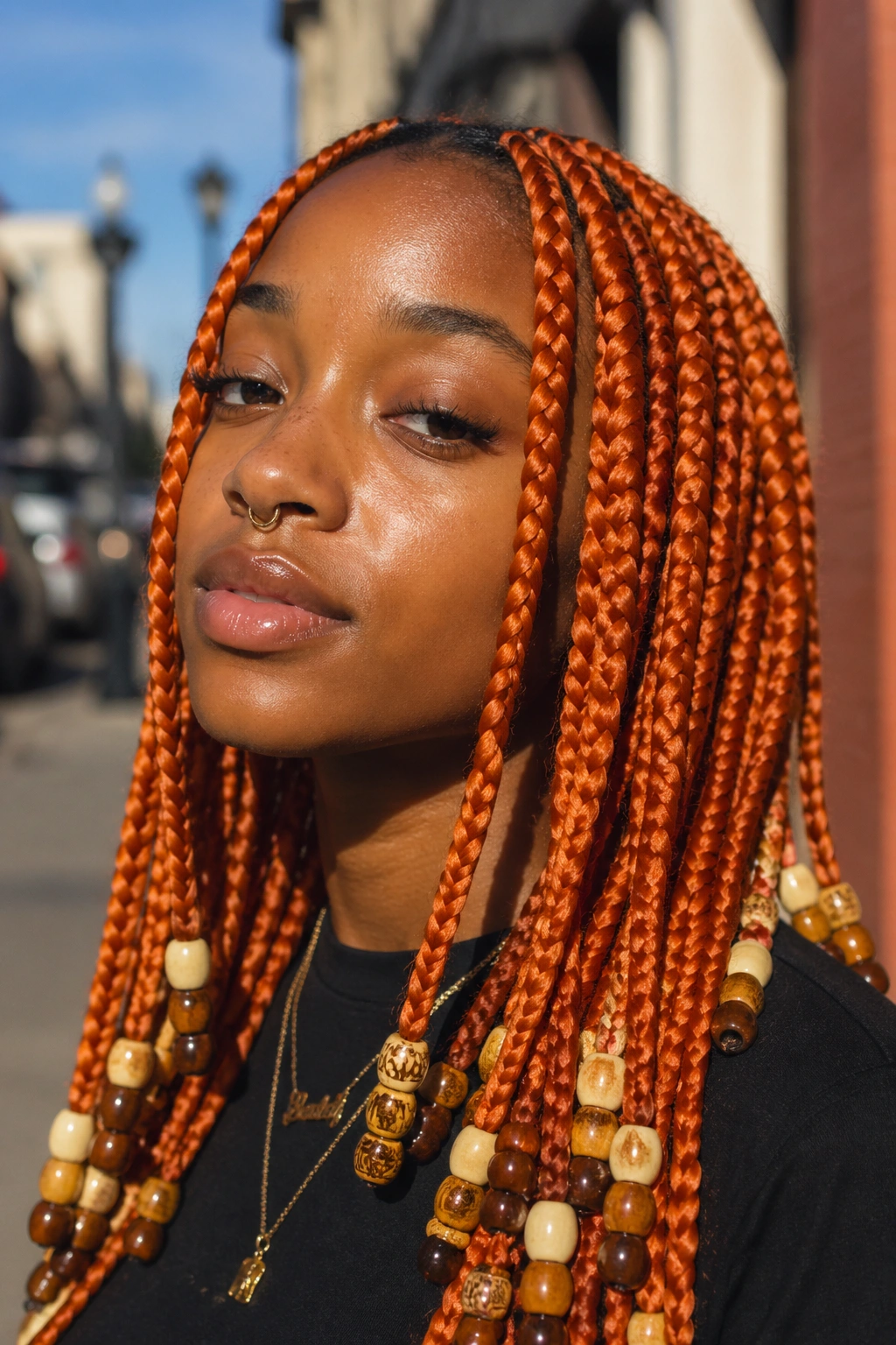 Portrait of a real person with chunky orange box braids and bead stacks at the ends