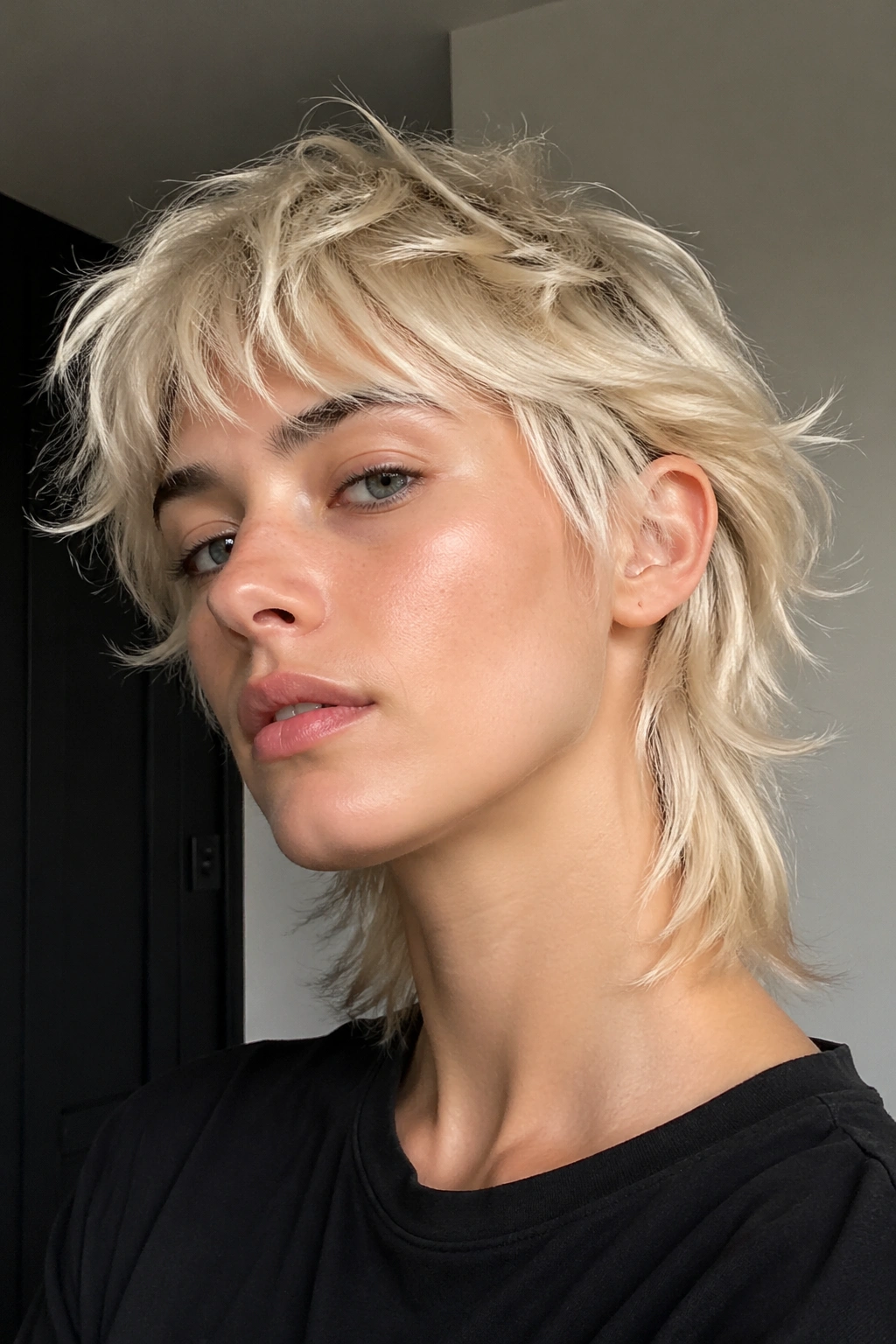 Close-up portrait of a real person with platinum piecey mullet under soft lighting