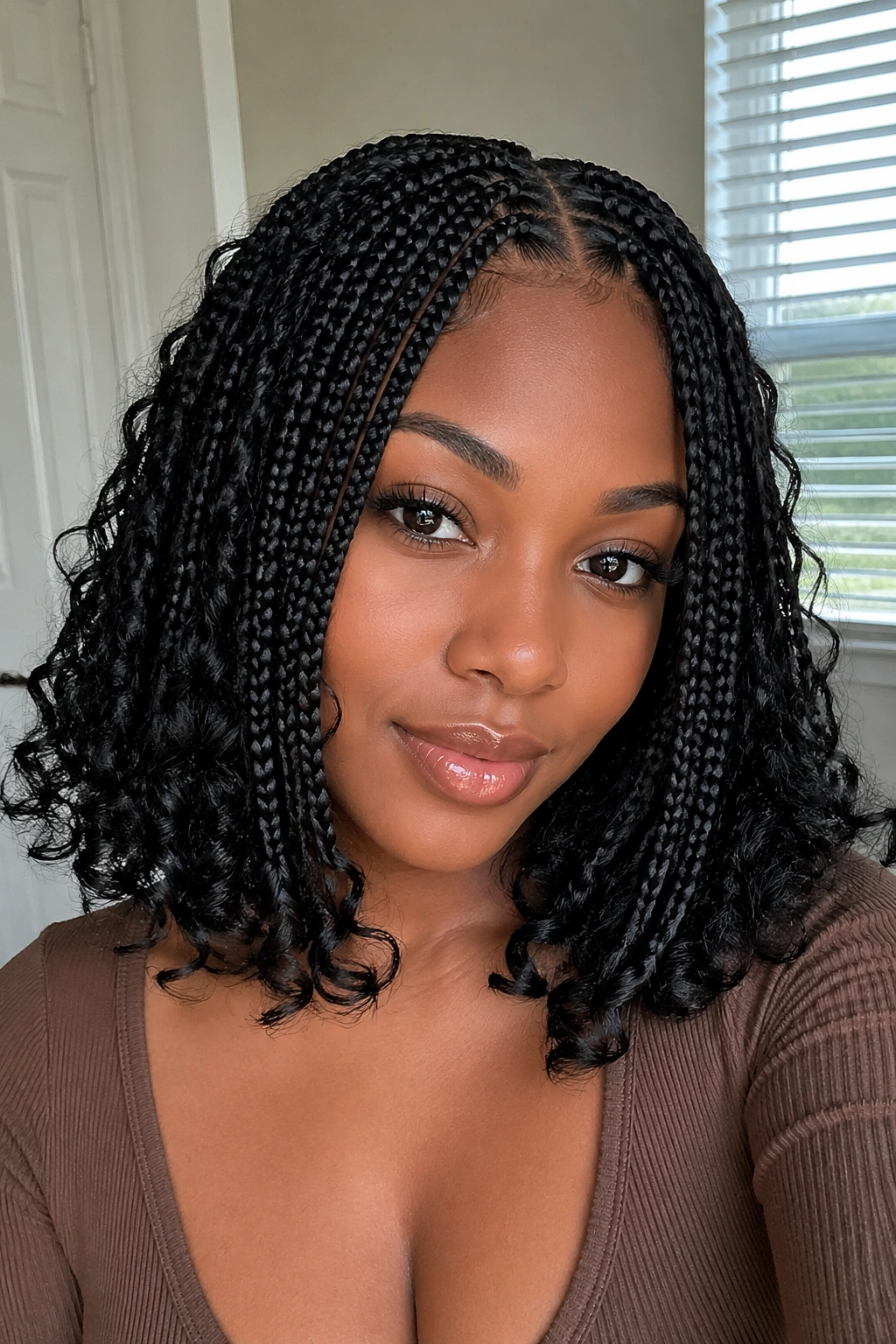 Close-up of a real woman with shoulder-length knotless braids and curly ends