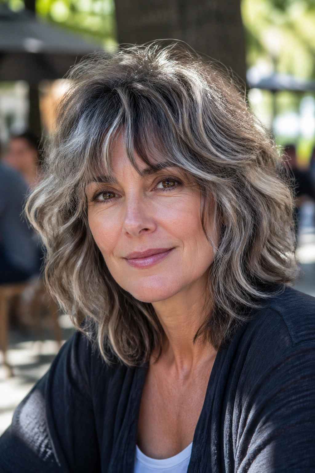 Portrait of a real woman with a wavy shag and ash-brown lowlights in natural light.