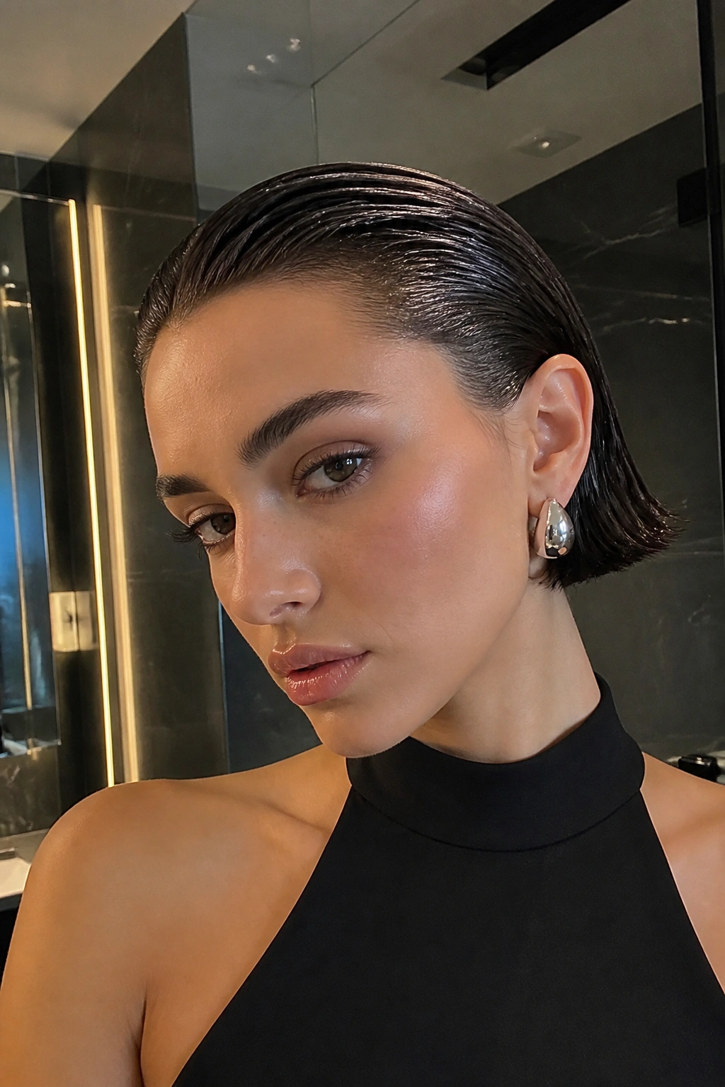 Close-up of a woman with a glassy wet-look slicked-back bob.