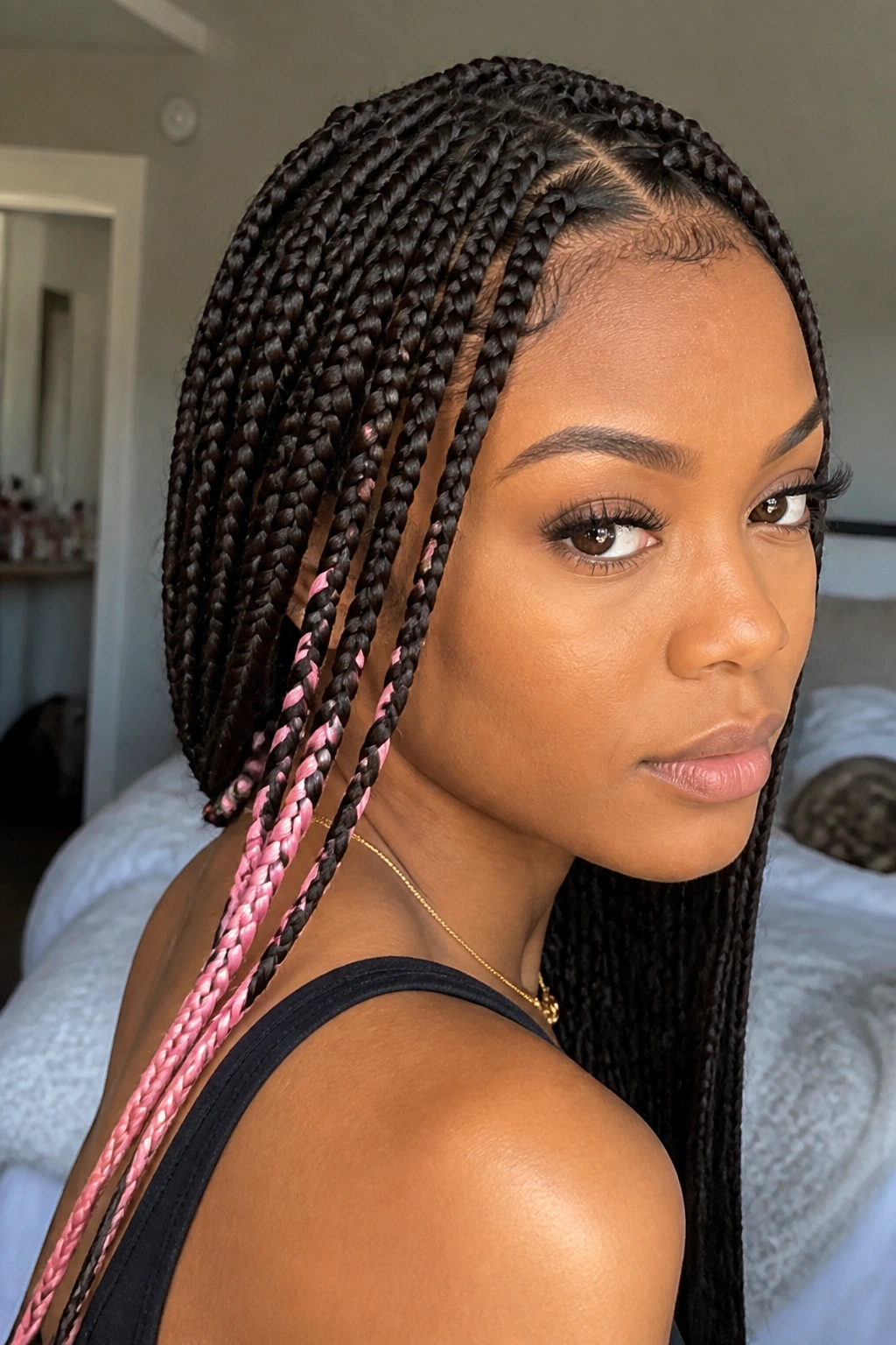 Close-up of pastel pink accent braids among dark hair on a real woman