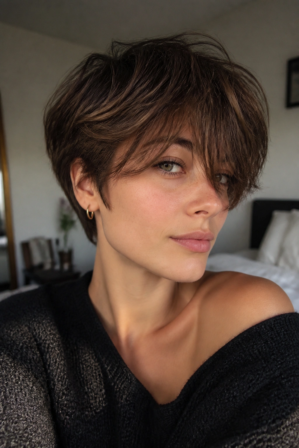 Close-up portrait of a real woman with a tousled crop and long fringe under natural window light
